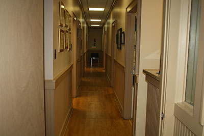 An interior hallway of a hospital, featuring a long corridor with doors on either side and a carpeted floor.