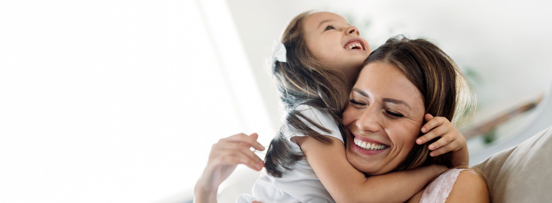 The image shows a woman embracing a child, both smiling and appearing happy.